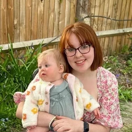 Charlotte, founder of The Little Planets, smiling with a baby on her lap